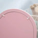 Back of pink kids vanity table mirror with visible screws, blurred teddy in background