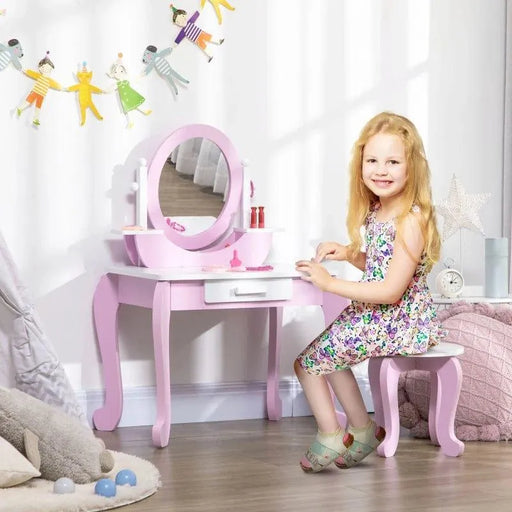 Smiling girl at pink kids vanity table with mirror, stool, drawer, and play makeup in bright room