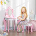 Smiling girl at pink and white kids vanity table with mirror and storage in bright bedroom