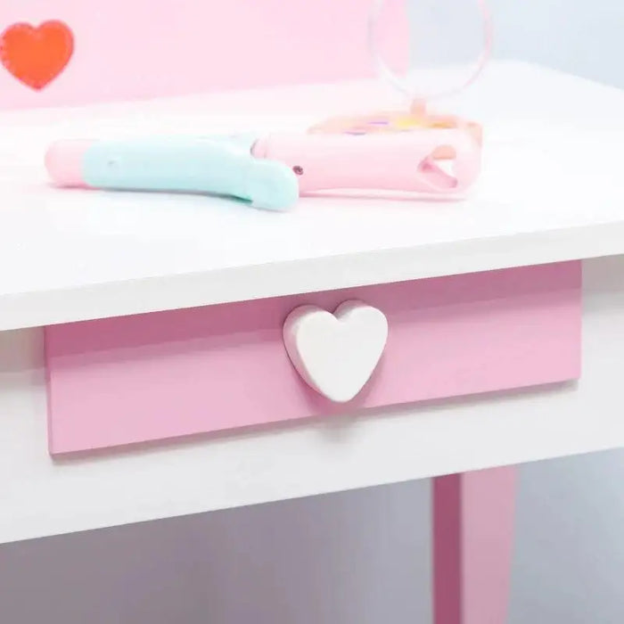 Pink and white kids vanity table with heart-shaped drawer handle and toy accessories
