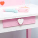 Pink and white kids vanity table with heart-shaped drawer handle and toy accessories