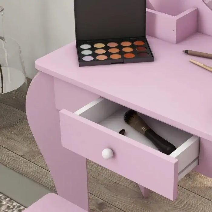 Pink kids vanity table with open drawer, makeup palette, brush, and wooden floor
