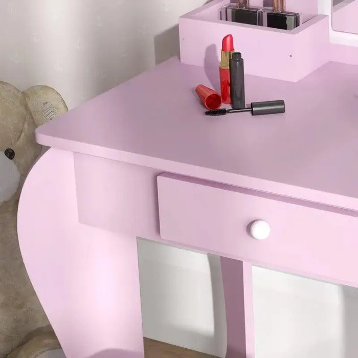 Pink kids vanity table set with drawer, lipstick, mascara, and teddy bear beside it