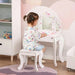 Child sitting at white kids vanity table set with triple mirror, stars and hearts design, and stool
