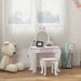 Kids white and pink vanity table with bunny ear mirror and matching stool in playroom