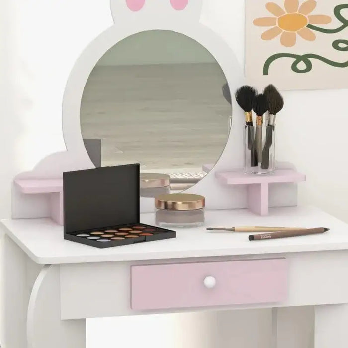 Kids white and pink vanity table with bunny mirror, makeup, brushes, and a painted flower wall art