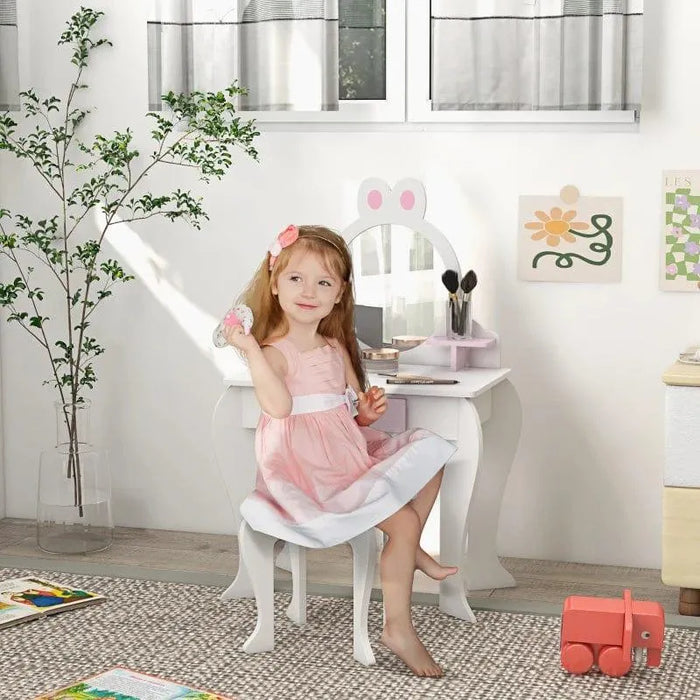 Girl at white and pink kids vanity table with bunny stool, mirror, and drawer in bright room