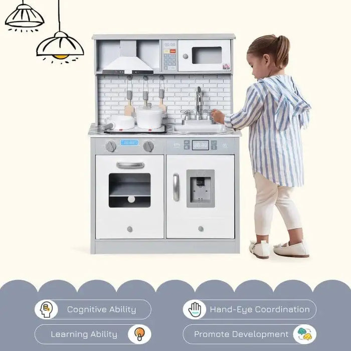 Child playing with grey and white wooden kitchen playset featuring toy sink and stove