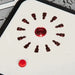 Close-up of red play stove burner on kids' wooden kitchen playset with marble pattern.