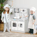 Kids chef costumes playing with grey and white wooden toy kitchen playset with marble countertop