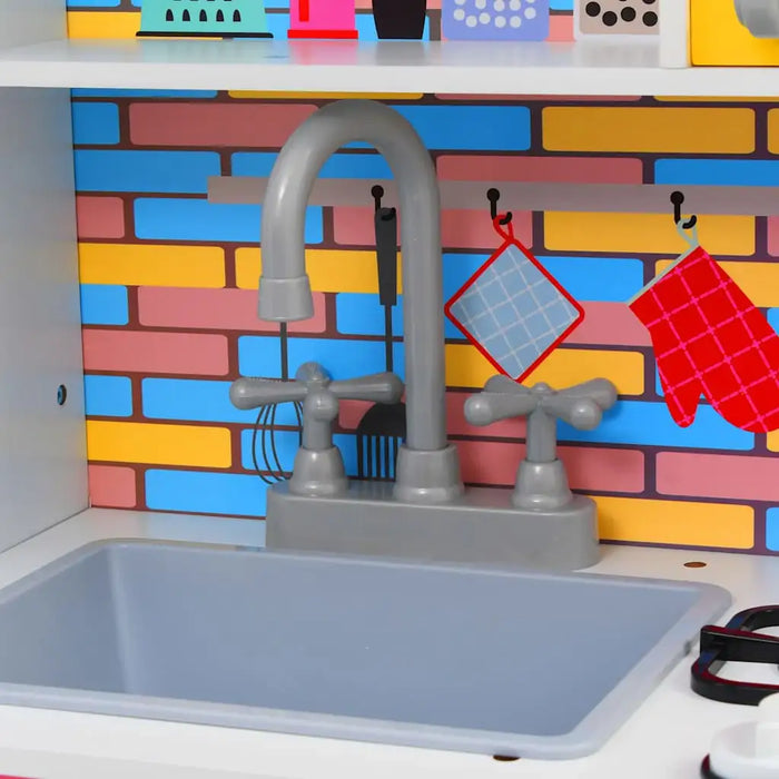 Kids play kitchen sink with gray faucet, colorful brick backsplash, and toy utensils
