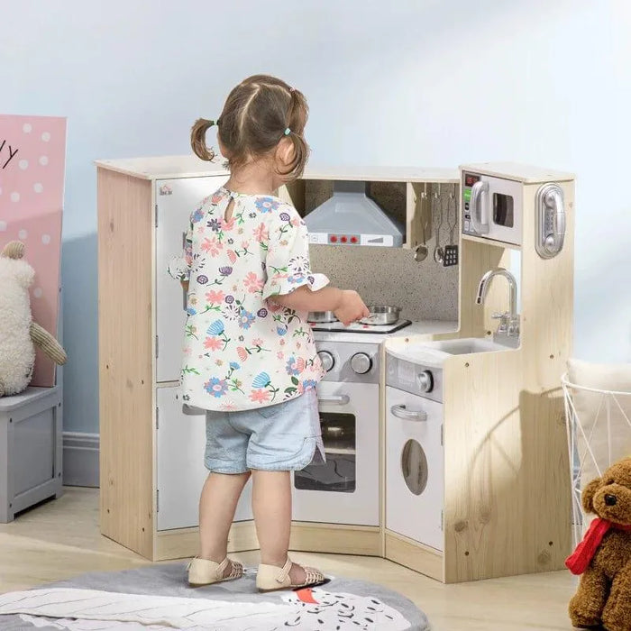 Little girl playing with natural and white wooden kids kitchen playset with storage and stainless steel accessories