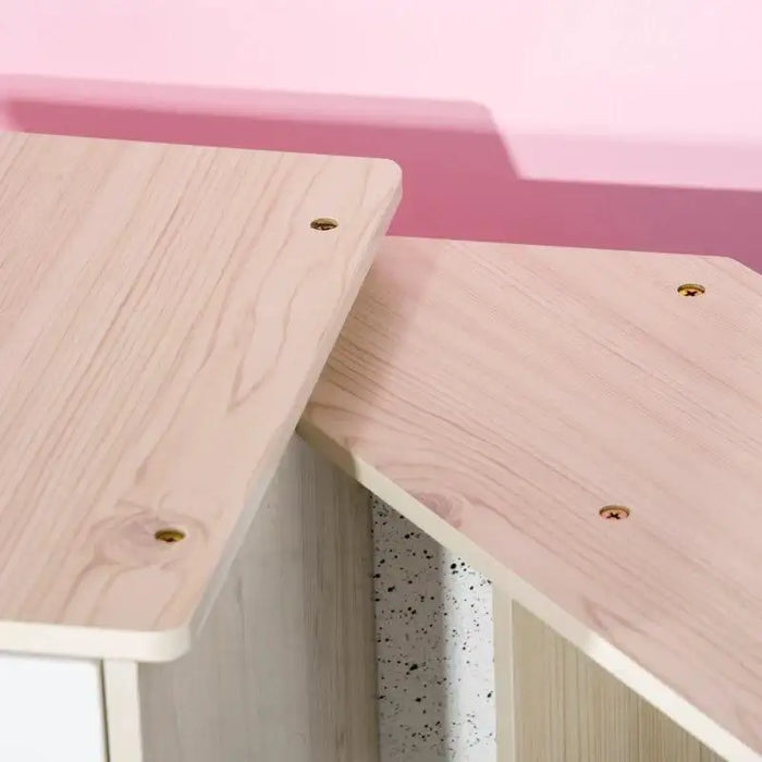 Light wood tabletop detail from kids wooden kitchen playset against pink wall
