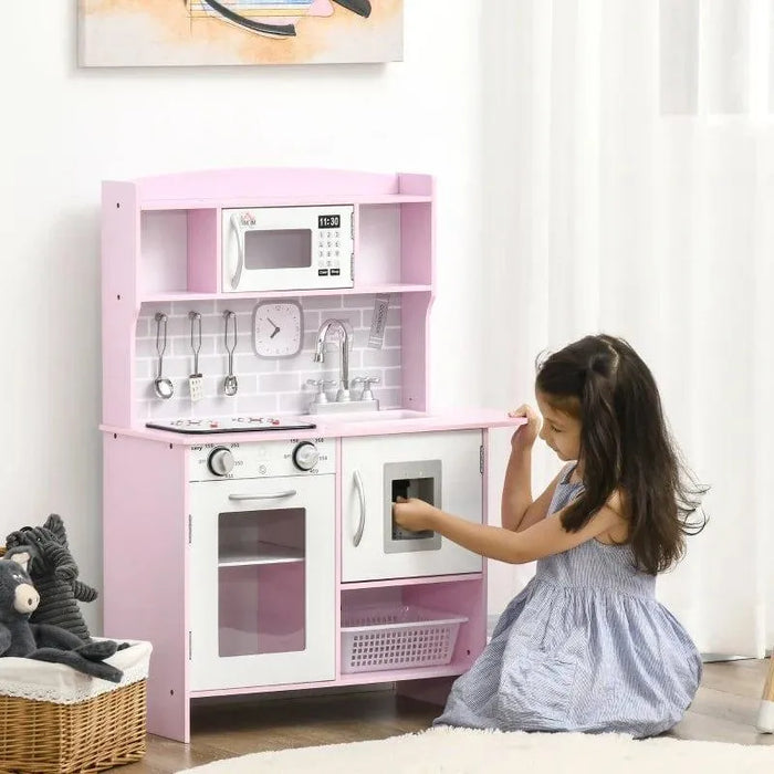 Girl playing with pink wooden kids kitchen playset featuring toy clock, sink, and storage
