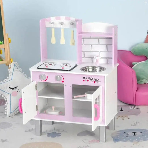 Pink wooden kids kitchen playset with utensils, sink, and stove in a playroom setting
