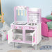 Pink wooden kids kitchen playset with utensils, sink, and stove in a playroom setting