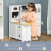Child playing with white wooden kids kitchen playset featuring accessories and sink