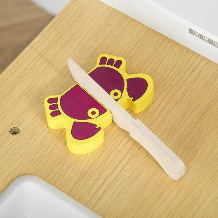 Wooden play knife cutting a yellow and purple toy crab on a kids kitchen playset countertop