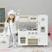 Child in chef costume with white wooden play kitchen set, water dispenser, and utensils