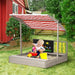 Child playing in grey wooden sandbox with canopy, board games, and chalkboard outdoors