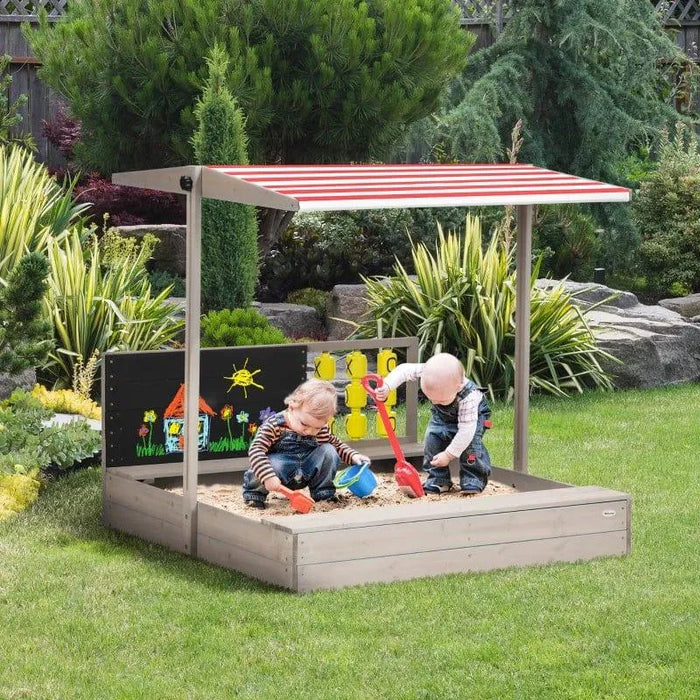 Children playing in a wooden sandbox with adjustable canopy and chalkboard in garden