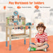 Smiling child with striped shirt next to kids wooden tool workbench playset with toy tools.