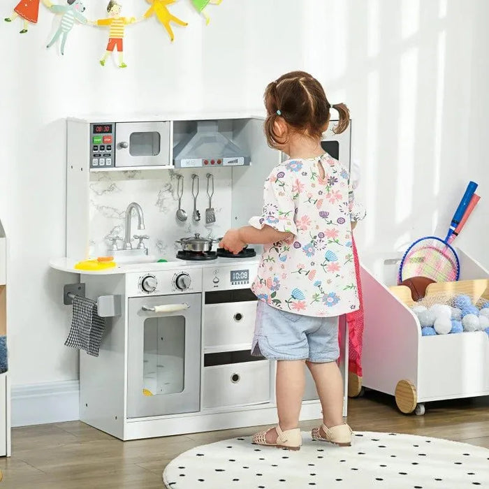 Child playing at white wooden toy kitchen with chef accessories and storage