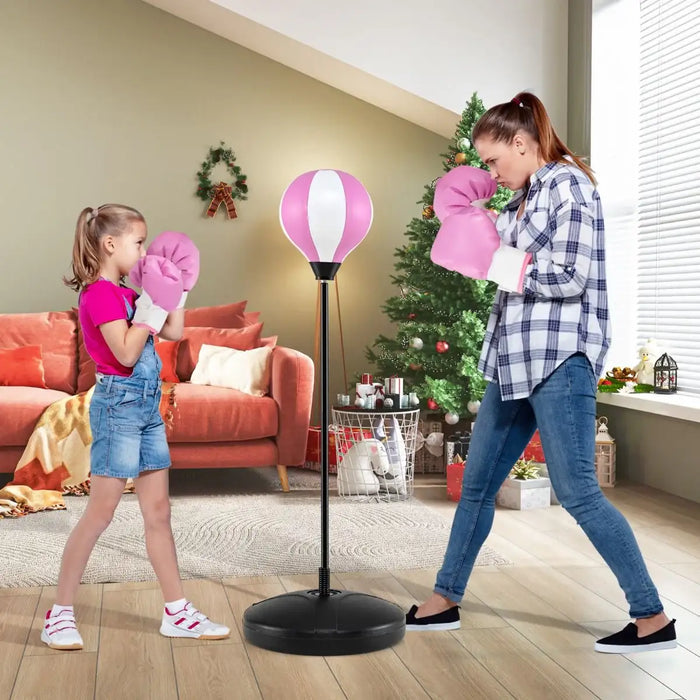 Woman and girl wearing pink boxing gloves standing in living room with punching bag and Christmas tree