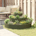 Three-tier olive green cylindrical steel planter with flowers in a cozy backyard seating area