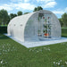 Large walk-in greenhouse polytunnel with mesh cover on lawn, shelving with plants inside