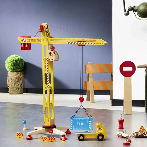 Large wooden yellow construction crane toy by Vilac with accessories and truck indoors