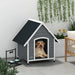 Large grey and black wooden dog kennel with slanted roof, dog inside, outdoor pet house