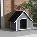 Large wooden dog kennel in grey and black with slanted roof for outdoor pets on patio