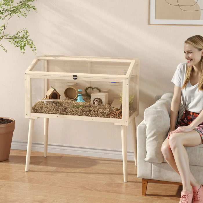 Woman sitting on a couch next to a transparent pet cage with a small animal inside, in a home setting.