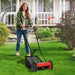 Woman using a red lawn mower on a green lawn in front of a house.
