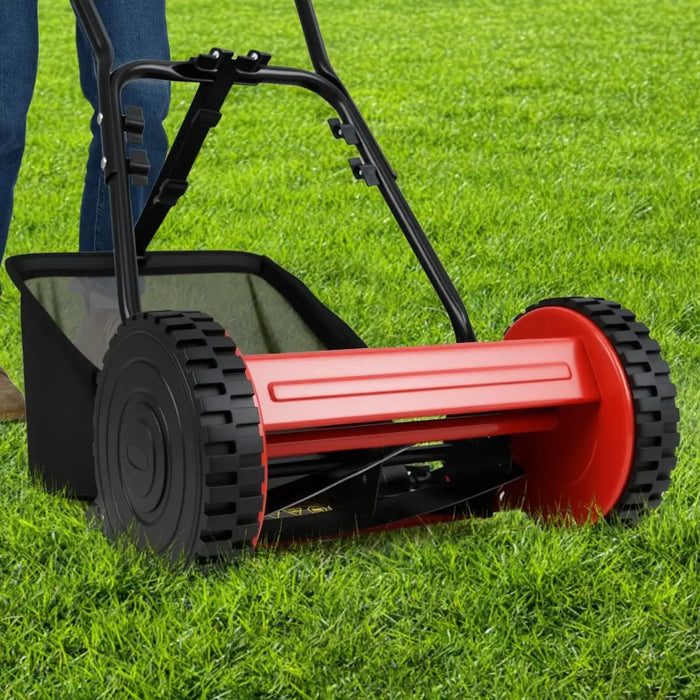 Red and black lawn roller on a grassy surface