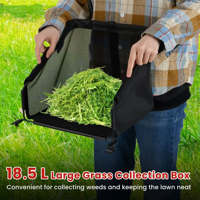 Person holding a black grass collection box filled with green grass against a grassy background.