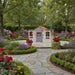 French-inspired playhouse with red roof in a lush garden of colorful flowers and stone path