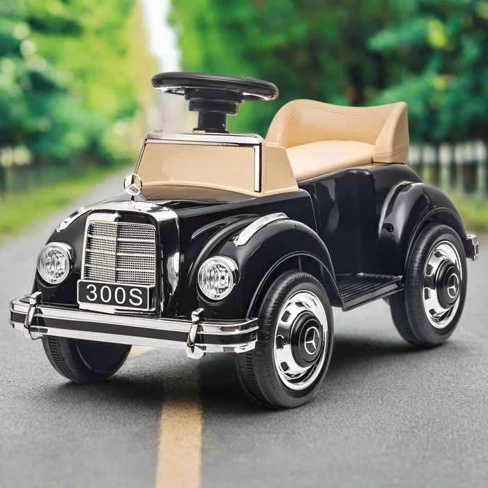 Black Mercedes-Benz 300S kids sliding car with beige seat on outdoor road.