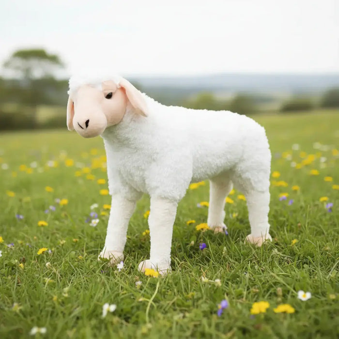 Stuffed lamb toy in a grassy field with flowers