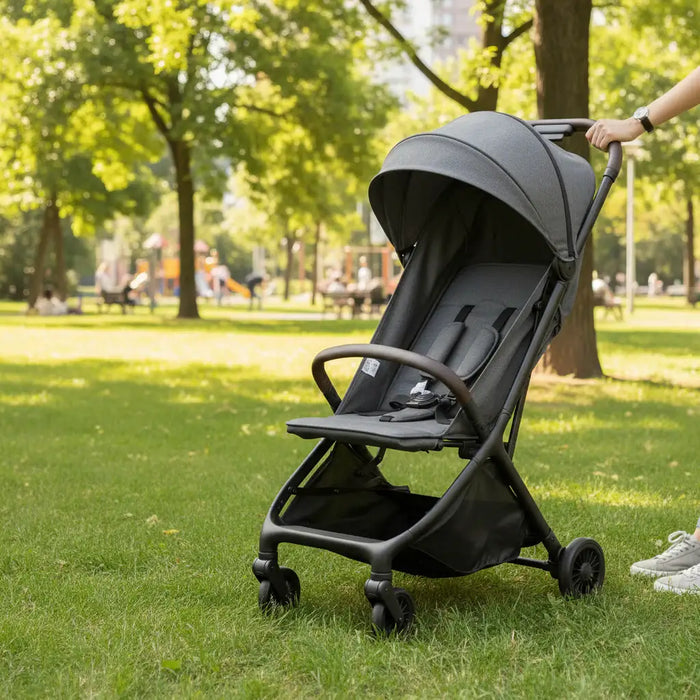 Gray stroller on grass with a park in the background