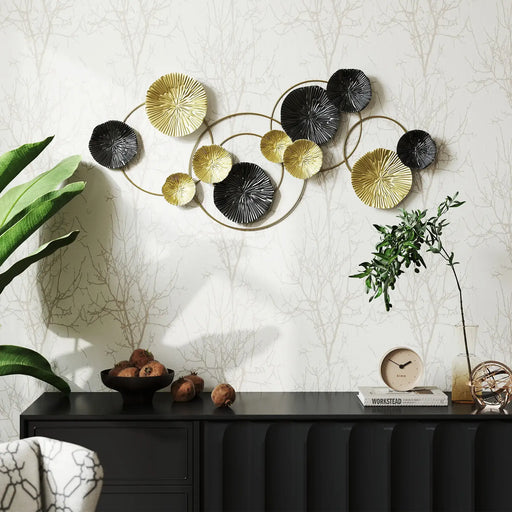 Decorative wall art with circular metal designs in gold, black, and silver on a textured wall.