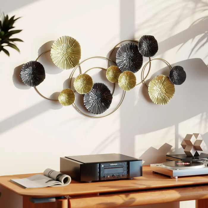 Decorative wall art with circular designs in gold, black, and gray on a white wall above a wooden desk.