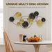 Decorative wall art with gold and black discs above a dining table with fruit and cups.