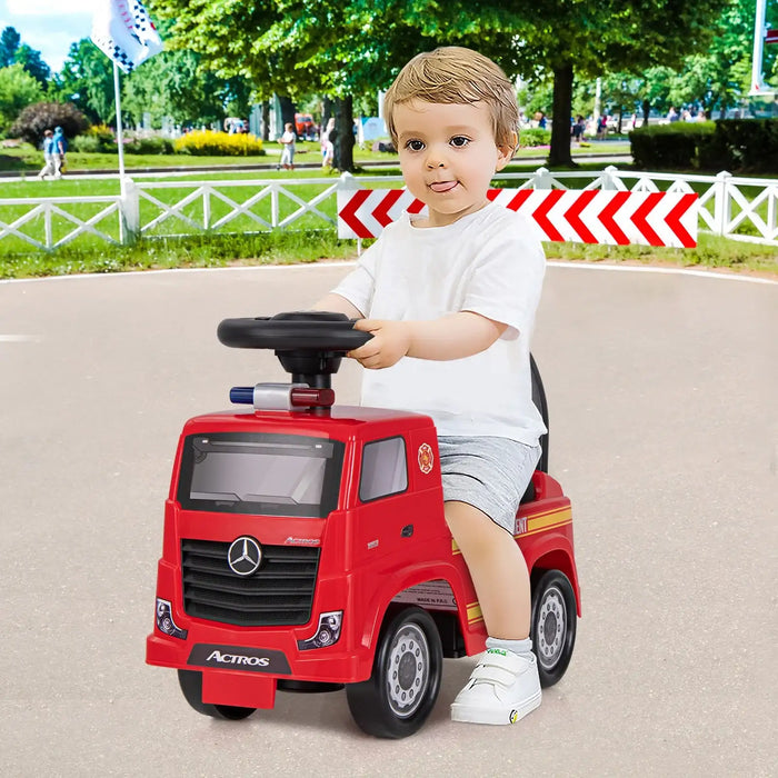 Child sitting on a red toy truck in an outdoor setting