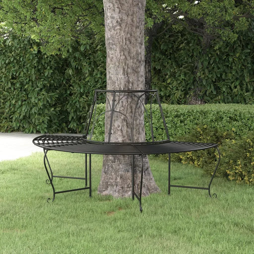 Black metal half-round wrap-around tree bench on green grass with leafy garden background