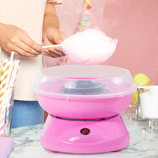 Pink cotton candy maker with fluffy pink cotton candy on a white surface.