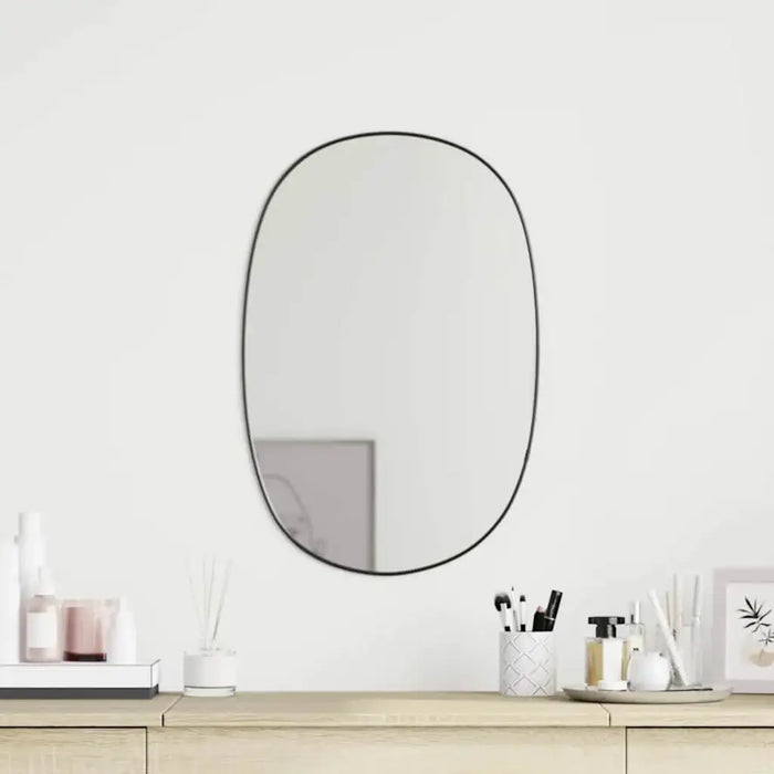 Round mirror on a white wall above a wooden shelf with decorative items.