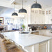 Modern kitchen with white countertops, gray pendant lights, and a large island.