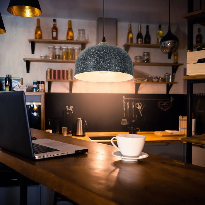 Laptop on a wooden table with a cup of coffee in a cozy bar setting.